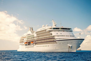 Large luxury white cruise ship liner on sea water and cloudy sky background